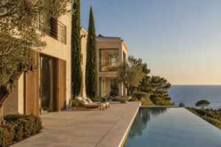 Light-stone villa overlooking the sea, with a long infinity pool bordered by cypresses and an umbrella pine