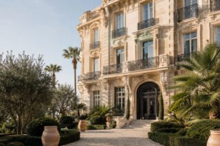 Carved stone Belle Époque façade, wrought-iron balconies and a gravel drive lined with urns and palms