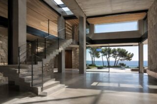 double-height villa interior with stone walls, a timber ceiling and a window opening onto the sea